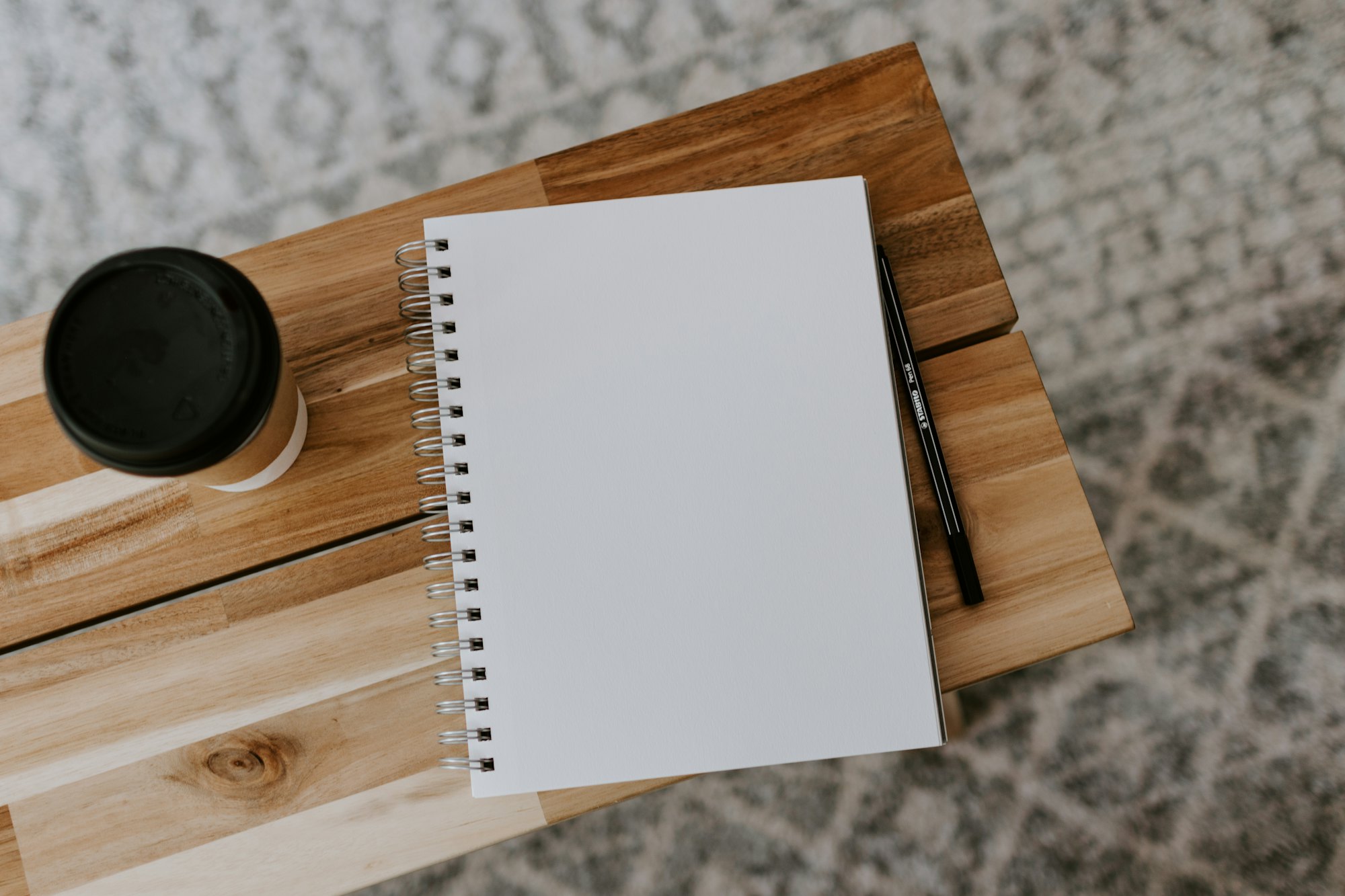 Open notebook and coffee on a warm wooden desk, top-down