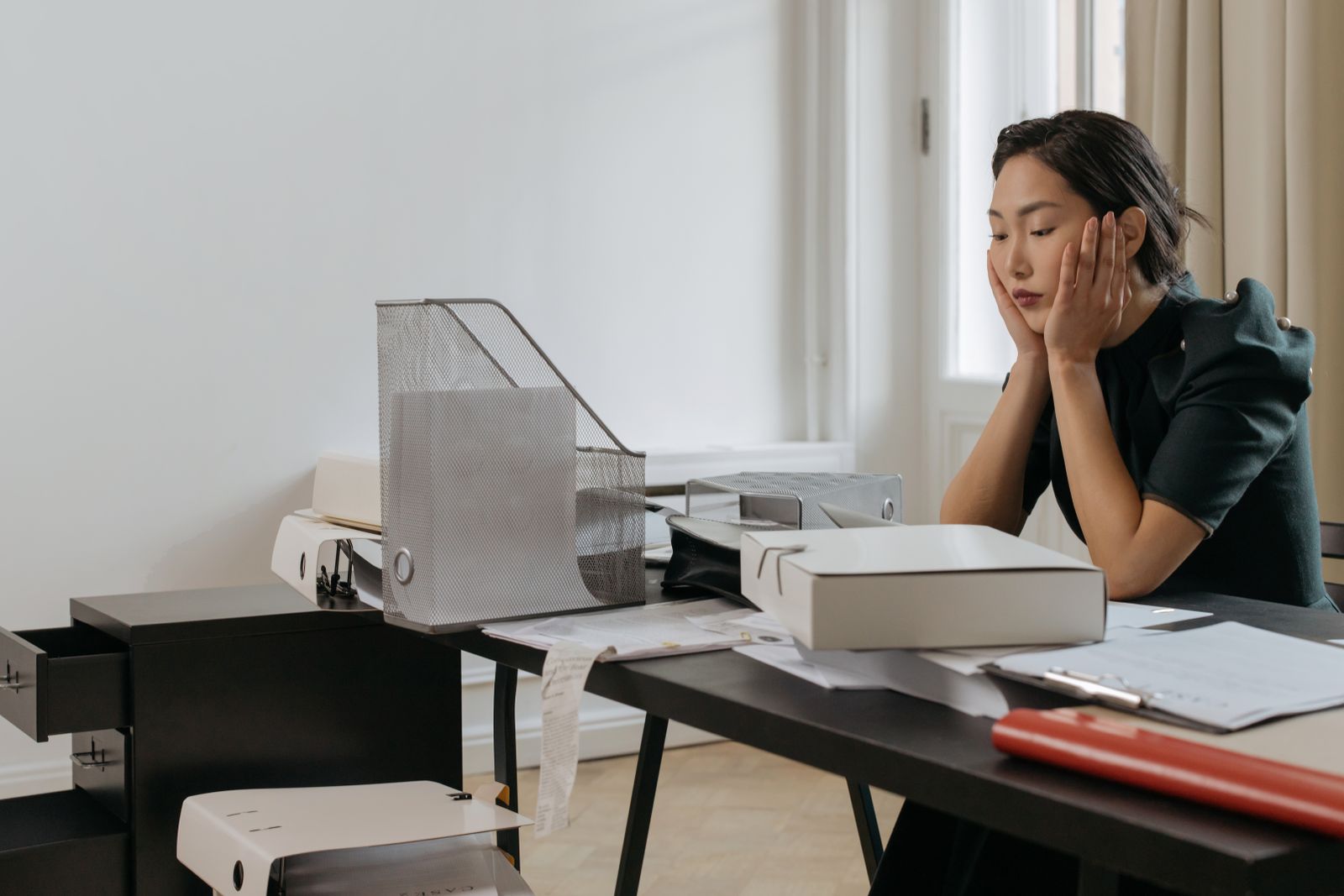Office worker slumped at a desk buried in binders and case files